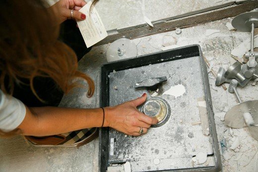 Woman holding a piece of paper, trying to open a safe.
