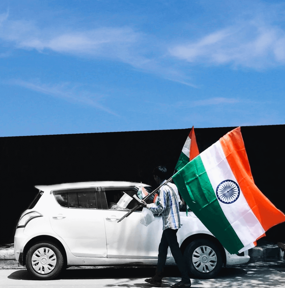 Man by Car Holding Flag of India.